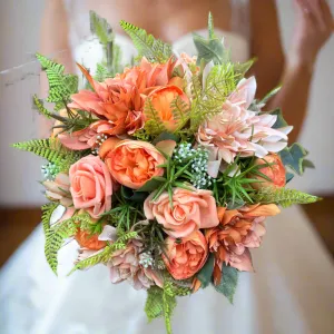 A brides bouquet featuring dahlia, ranunculas and roses