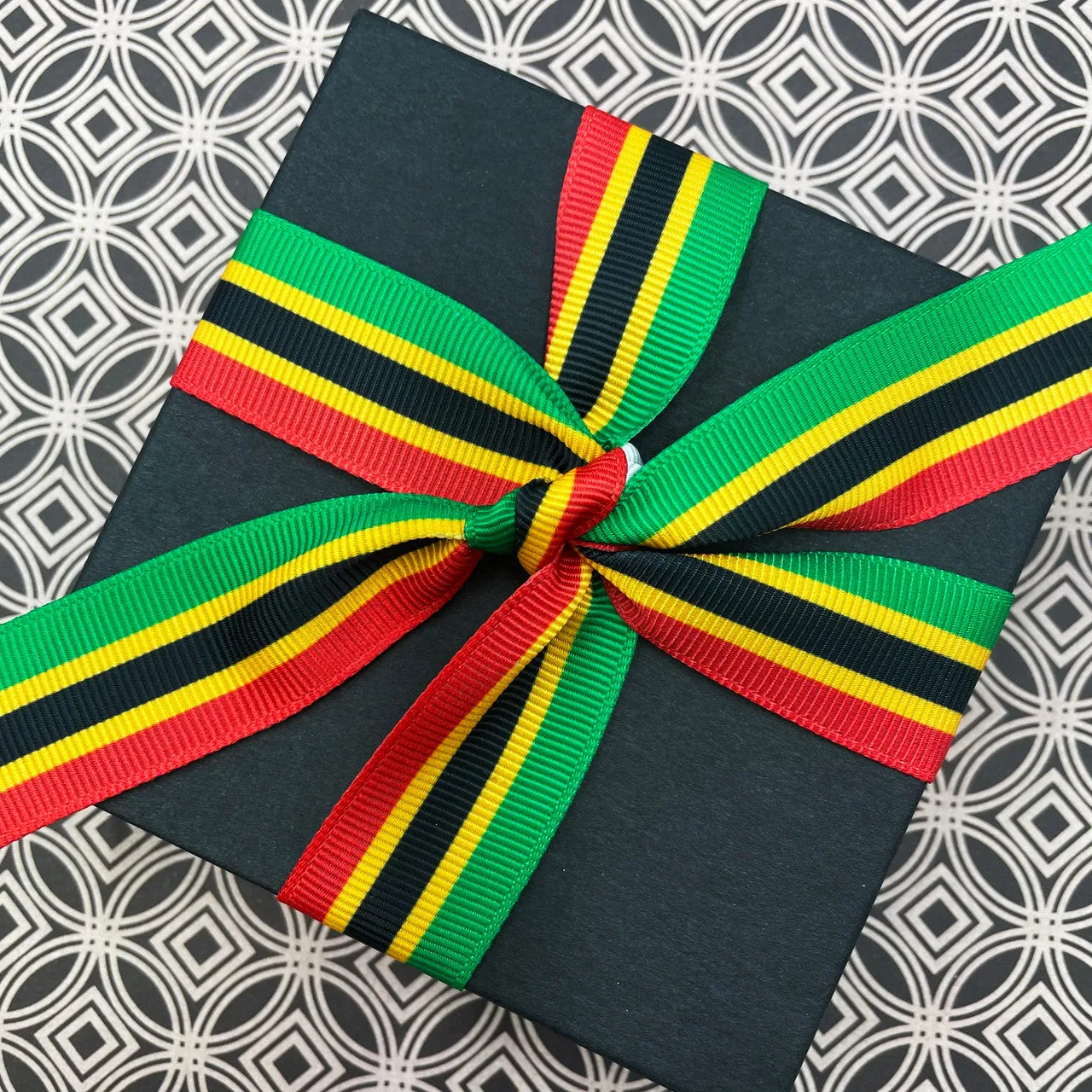 Kente Stripe ribbon in red, black, green and yellow printed on 7/8" white grosgrain