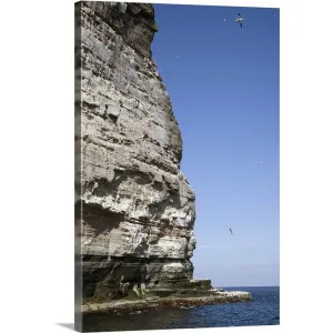 "a tall rock face on the water's edge" Canvas Wall Art